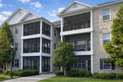 Two apartment buildings with balconies and trees in front.